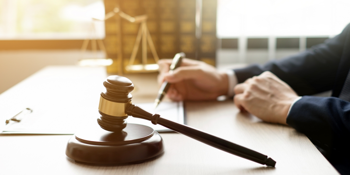A lawyer filling out forms with a judge's gavel in front of him