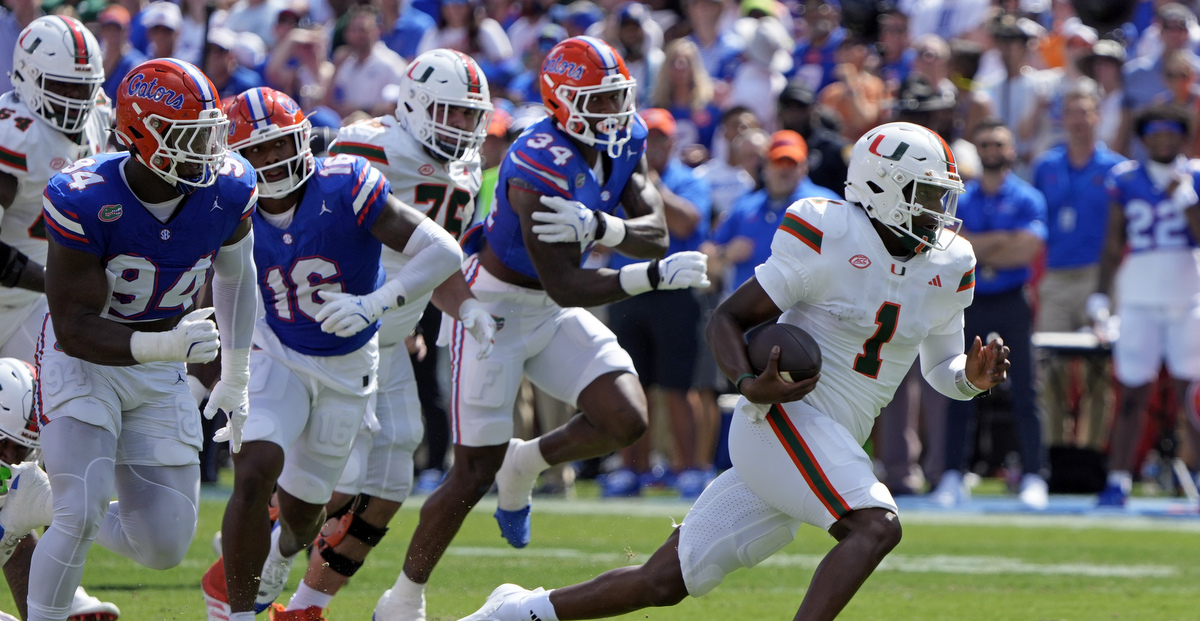 Miami quarterback Cam Ward runs by Florida defenders