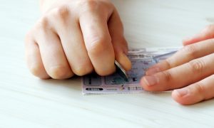 Someone using a coin to play a scratch-off lottery ticket